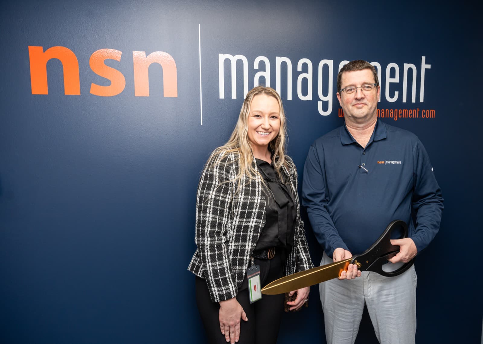 Two NSN Management team members celebrating at the logo wall